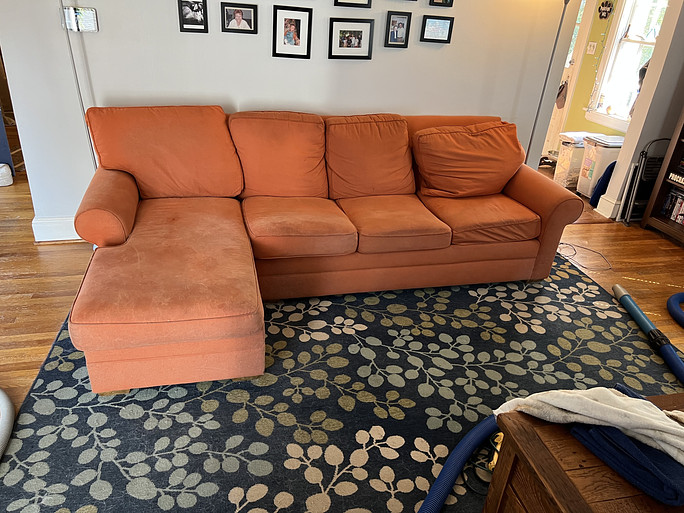 Couch cleaning in Roanoke, VA, home is about to begin on this orange sofa that shows signs of wear and tear as well as stains.