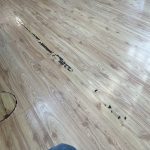 Black adhesive on a light hardwood floor, Quest Floor Care was called in to provide advhesive removal service